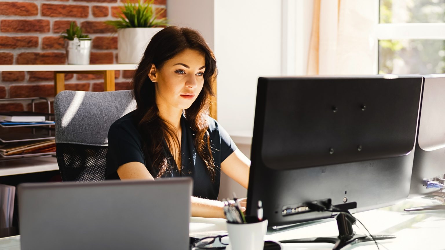 On voit une femme entrain de travailler dans son bureau sur un ordinateur